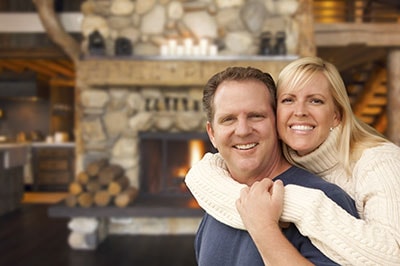 Happy Affectionate Couple at Rustic Fireplace in Log Cabin